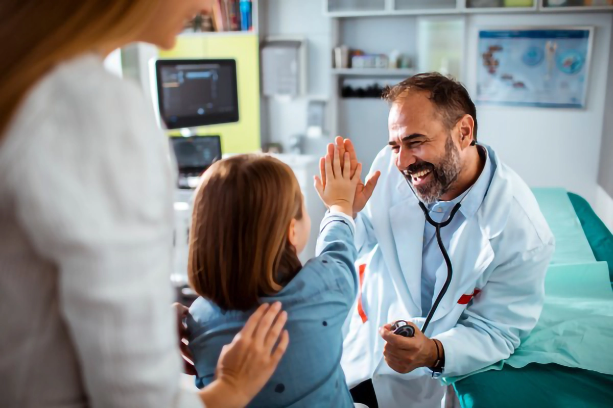 Image of a doctor with a young patinet smilling and high-fiving