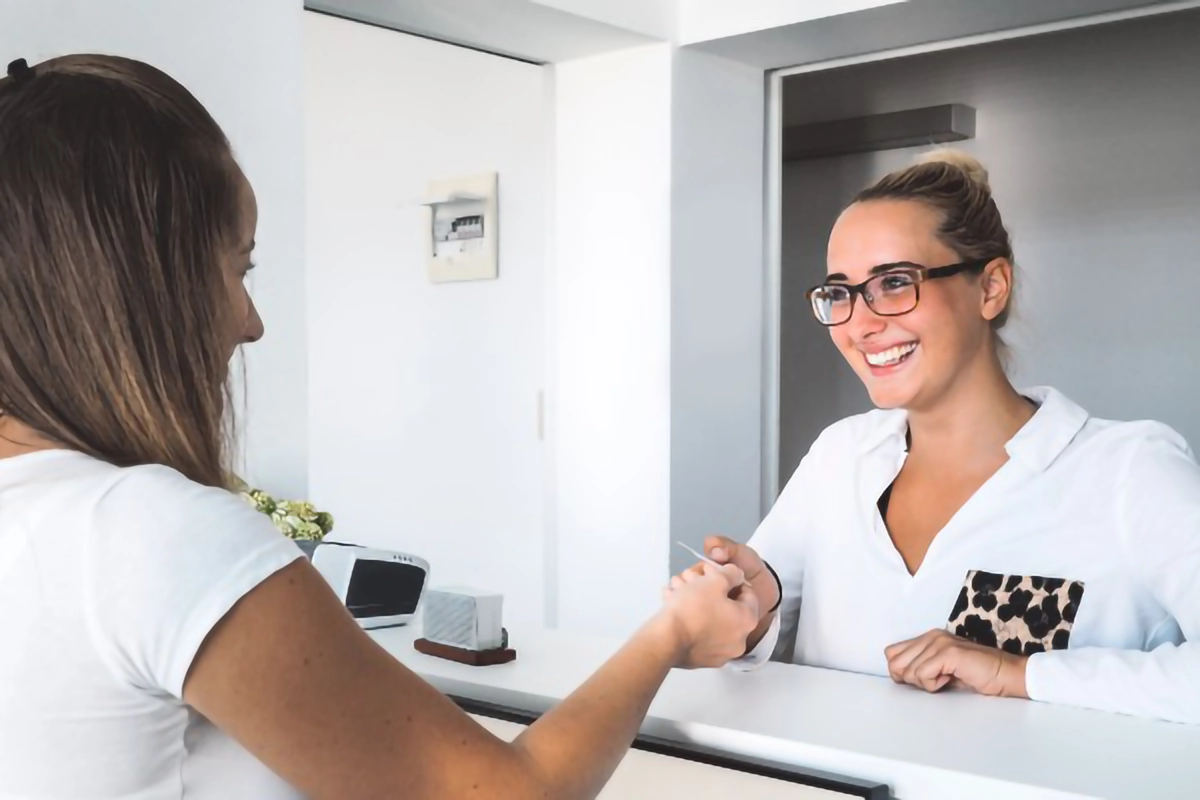 Image shows a patient registering at the surgery at the front desk